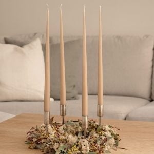 Adventskrans med stagelys i brun-beige. Adventskransen står på et sofabord i en stue.