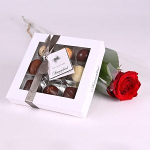 Chokoladeæske og en rød rose pakket i cellofan.