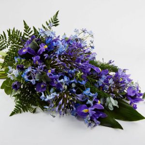 Bårebuket af årstidens blomster i blå/lilla farver.