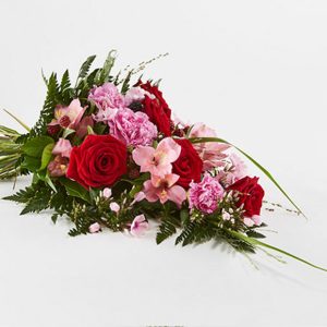 Bårebuket af årstidens blomster i rød og lyserød.