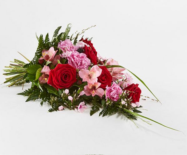 Bårebuket af årstidens blomster i rød og lyserød.
