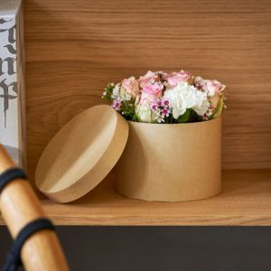 En lyserød blomsteræske i beige æske, stående i reol