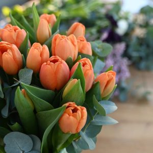 Close-up af buket orange tulipaner i en gennemsigtig glasvase.