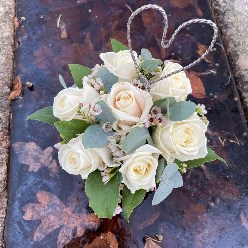 Hvid blomsteræske med hjerte af metaltråd som pynt set oppefra