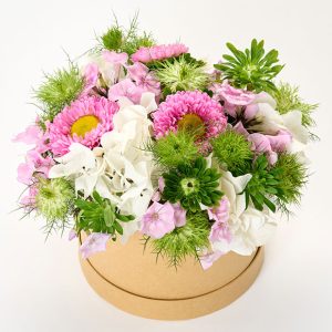 Sommerdekoration i lyse farver i en rund blomsteræske.
