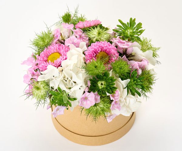 Sommerdekoration i lyse farver i en rund blomsteræske.