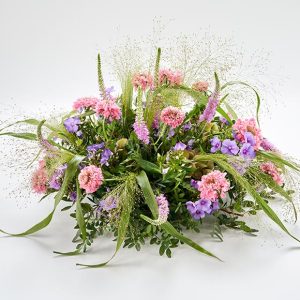 Blomsterpude til begravelse. Dekorationen er rund og luftig i lyserøde og lilla.