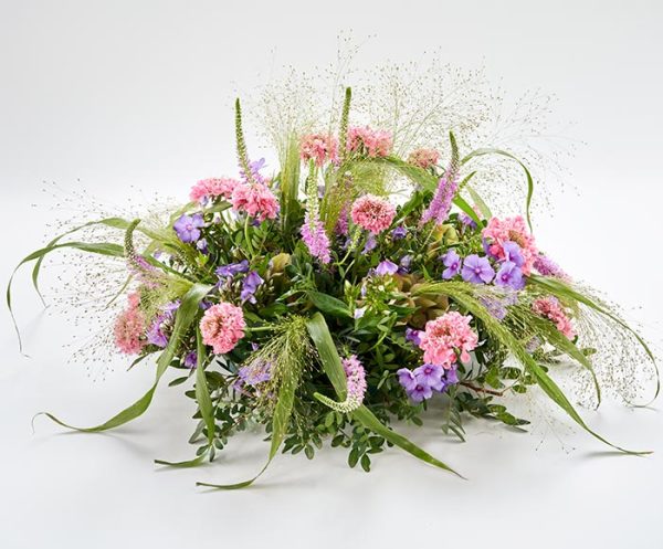 Blomsterpude til begravelse. Dekorationen er rund og luftig i lyserøde og lilla.