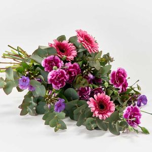Bårebuket med blomster i pink og lilla.