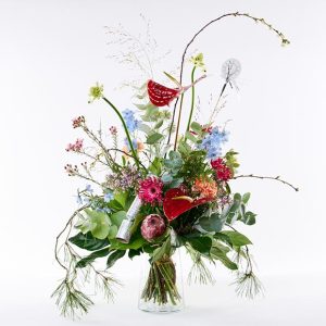 Variationsbuket i ekstraordinær stor størrelse. Buketten er bundet af mange forskellige blomster i friske farver og pyntet med en nytårsknallert i sølv.