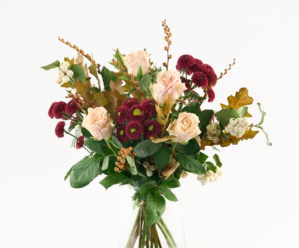 Luftig buket i gyldne og lyse nuancer af bl.a. roser, monbretia, santini chrysanthemum og efterårsløv.