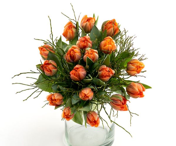 Buket orange tulipaner i en gennemsigtig glasvase.