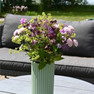 Sød lilla buket står på et havebord