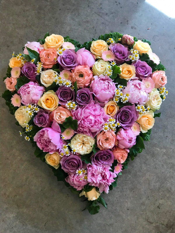 Et begravelseshjerte i lyserød, fersken og creme farver.