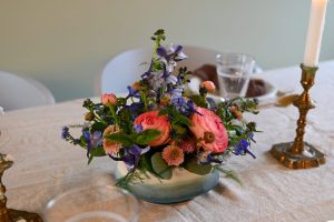 Borddekoration i blå og rosa nuancer. Dekorationen står på et pænt dækket bord.