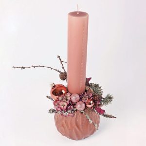 Rosafarvet kalenderlys med guldtal placeret i en keramikkrukke som er pyntet fint til en juledekoration.