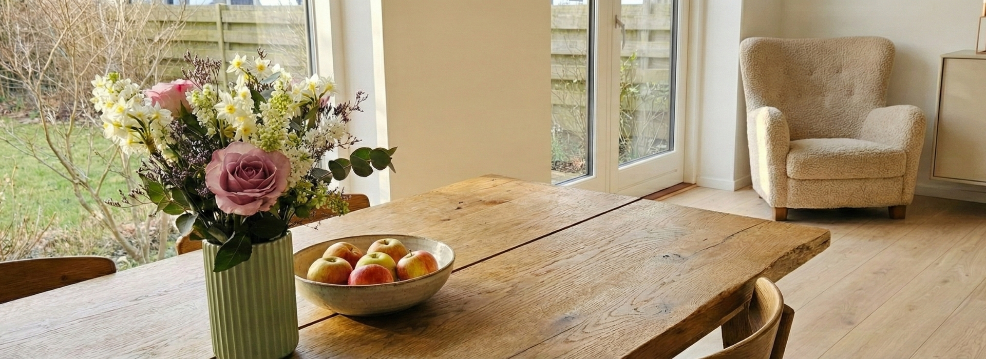 En smuk forårsbuket står på et spisebord i en hyggelig stue.