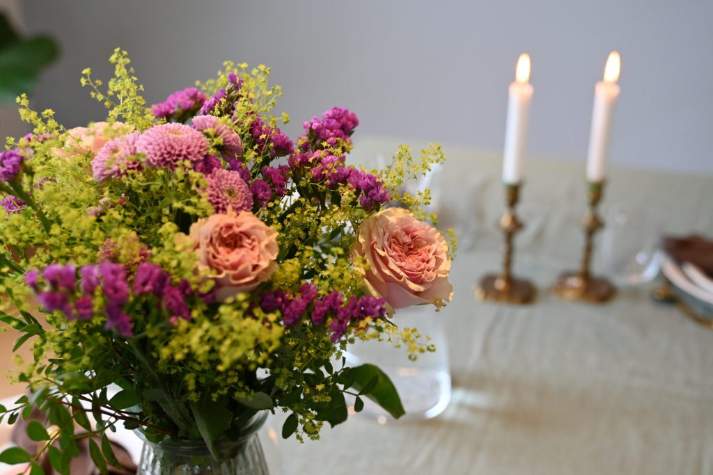 Lyserød og lime buket står i en glasvase på et bord.