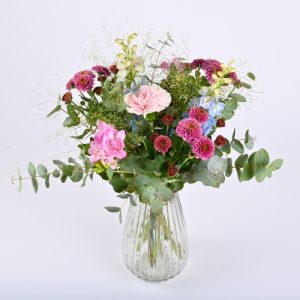 En buket, der står i en glasvase på en hvid baggrund.