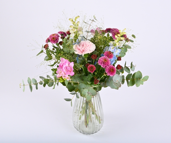 En buket, der står i en glasvase på en hvid baggrund.