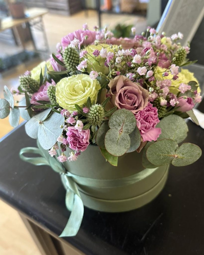 En grøn, rund æske med forskellige blomster.