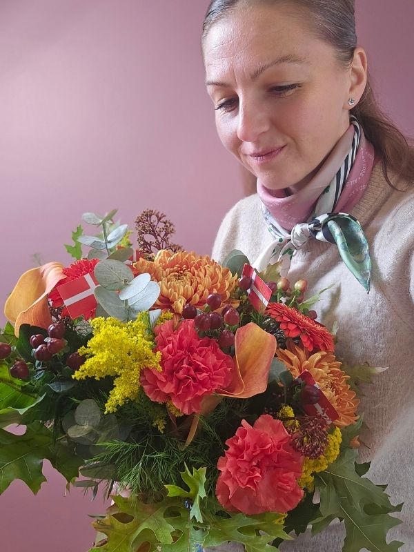 Blomsterdekoratør med en orangebuket i hænderne.