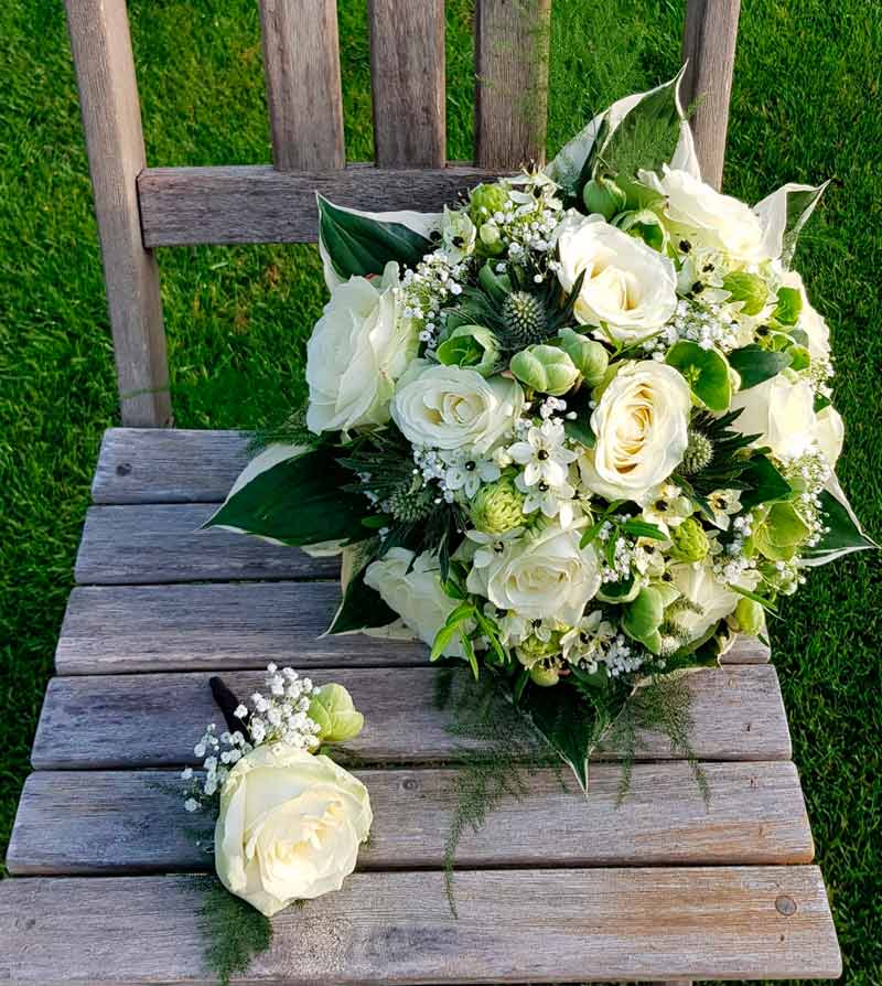 Hvid, rund brudebuket og en knaphulsblomst i matchende farve og blomster.