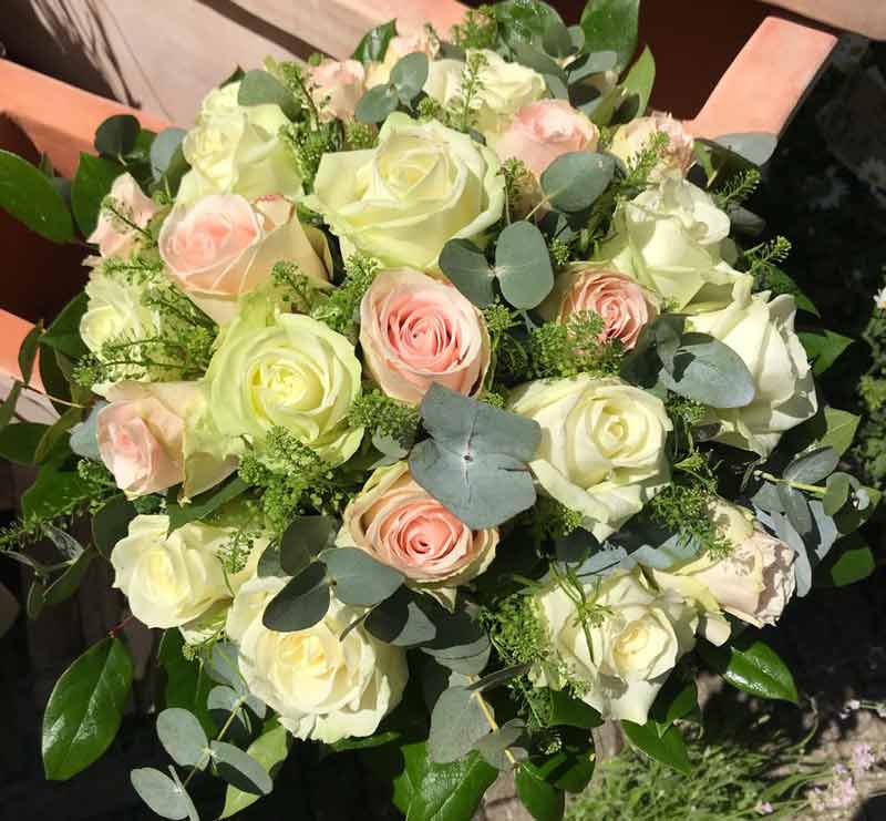 Rund rosenbuket med hvide og lyserøde roser bundet med fint grønt.